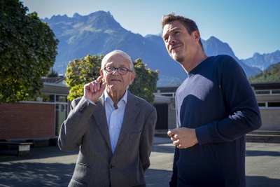 Karl Sillaber, Mitglied der Architektengemeinschaft C4, und Matthias Hein im Gespräch vor der imposanten Bergkulisse rund um die Volksschule in Nüziders, erbaut 1959–1963 von der Architektengemeinschaft C4.
