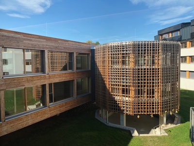 Das neue Wohnheim ergänzt das bestehende Schulensemble  und bietet den Schüler*innen einen großzügigen, hellen und freundlichen Lebensraum. Der zweigeschoßige Massivholzbau liegt auf Betonpfeilern, deren Rhythmus sich aus dem Raster der Zimmer ergibt. Unterschiedliche Raumfigurationen schaffen vielfältige Begegnungszonen und laden zum Austausch ein.