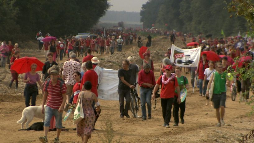 Tausende demonstrieren gegen Braunkohle. Im August 2017 bildeten 3000 Menschen eine rote Linie entlang der alten A4 und stellten sich damit schützend vor den Hambacher Forst.