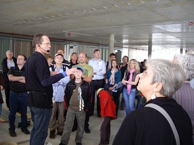 Baustellenführung "Bildung konsumieren" – Helmut Reitter führt durch das Nahversorgungszentrum "Q-West" und  "BRG in der Au"