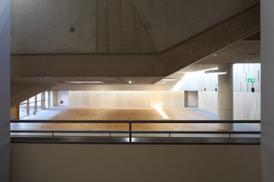 Bei der Sanierung wurde der Schulhof überdacht und damit ein großer, multifunktionaler Zentralraum geschaffen, der Foyer, Erschließung, Stiegenhaus, Pausenraum, Wartebereich, Nachmittagsbetreuung und Veranstaltungsraum in einem ist. Die prägende Waschbetonfassade des Altbaus wurde erhalten, woraus sich eine spannende Mischung von Alt und Neu ergibt.