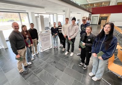 Architekt Peter Laimgruber und Schüler*innen der HLT Saalfelden betrachten gemeinsam die Ausstellung.