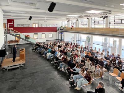 Roman Höllbacher (Künstlerischer Leiter Initiative Architektur) spricht vor Schüler*innen der HTL Saalfelden zur Abwicklung und Vergabe des Architekturpreis Land Salzburg.