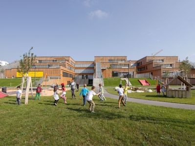 Der große Bildungsbau für ca. 800 Kinder und Jugendliche umfasst einen Kindergarten, eine Volksschule und Klassen für Schüler*innen mit besonderen Bedürfnissen. Am zentralen Hannah-Arendt-Platz im großen Stadterweitungsgebiet Seestadt Aspern gelegen, besticht der terrassenförmig angelegte Holzbau mit einem großzügigen Freiraumangebot, das viel Platz für Sport und Spiel bietet.